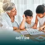 A therapist helping two autistic children complete a workbook activity with flashcards and learning materials at a table.