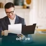Smiling professional therapist in glasses reviewing a document folder at a desk in a bright office setting.