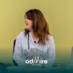 Female ABA therapist at desk smiling, holding hundred-dollar bills, symbolizing salary growth and earnings.