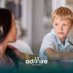 Two autistic kids sit at classroom table with pencils and notebooks, symbolizing inclusion and learning in mainstream school.