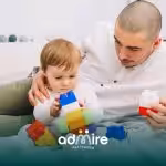 Autistic toddler plays with stacking toys as therapist supports, symbolizing early screening and autism evaluation.