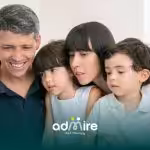 Therapists sitting closely with two autistic children while looking at a screen together, sharing a focused family moment.