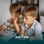 Two autistic kids sitting at a table with learning materials, representing cognitive development & early educational support.