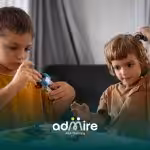 Two autistic kids playing with small toys together at a table, showing social interaction & varying developmental strengths.