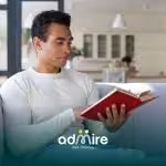 Male therapist reading a book in a calm home setting, representing learning, awareness, & understanding the history of autism