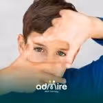 Autistic boy looks away while seated at table, illustrating social communication differences like reduced eye contact.