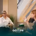 A therapist speaks to a client in an office, while the client, looking emotional, holds a tissue in a supportive conversation.