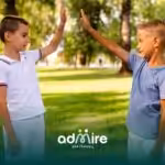Two autistic boys high-fiving in a sunny park, showing friendship, social interaction, and childhood behavior.