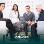 Group of therapists sitting together in a meeting, smiling & engaging in collaborative discussion in a modern office setting
