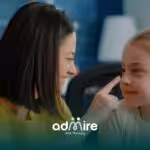 A therapist playfully pointing at an autistic girl as they share a joyful moment together, sitting across from each other.