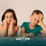 Two autistic kids sitting at a table working on a puzzle, showing different emotions like boredom and focus