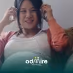 Pregnant woman sitting comfortably on a couch wearing headphones and smiling, representing relaxation.
