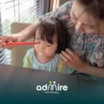 Therapist gently guiding autistic girl during structured activity at table, supporting focus and communication development