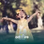 Happy young autistic girl in a yellow dress celebrates outdoors with confetti while smiling & raising her arms in excitement
