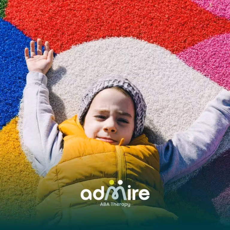 Autistic boy lying on colorful playground surface with arms stretched out, engaging sensory input and outdoor play activity