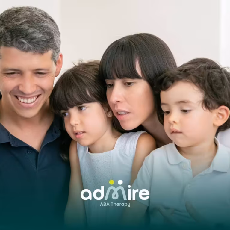 Therapists sitting closely with two autistic children while looking at a screen together, sharing a focused family moment.