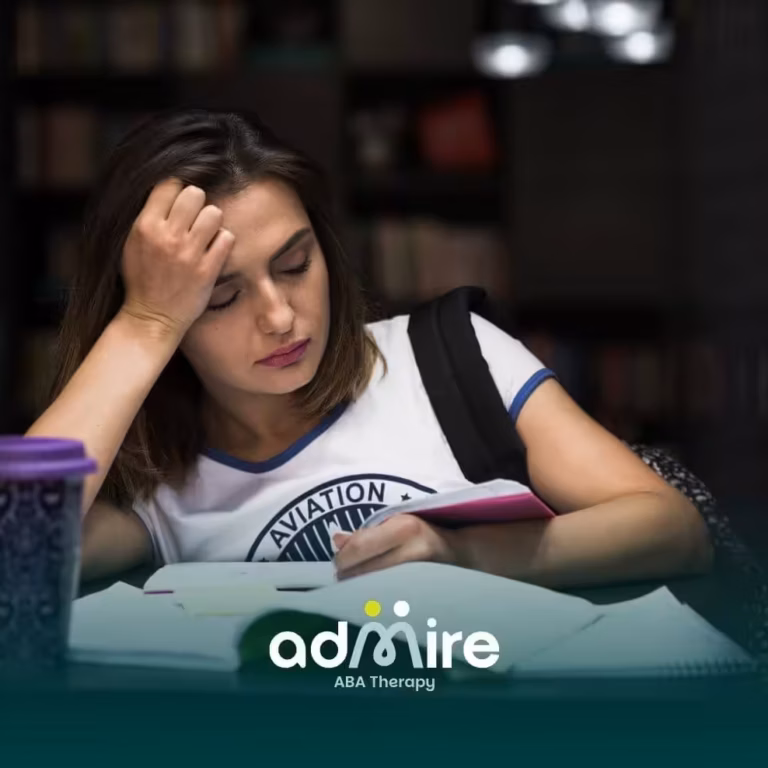Tired ABA student studying late at a library desk with notebooks and coffee, struggling to stay focused.