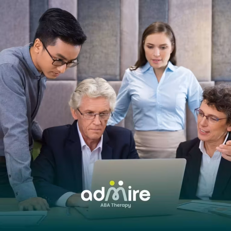 An ABA team gathered around a laptop during a meeting discussing reports and collaborating on project strategy in an office.