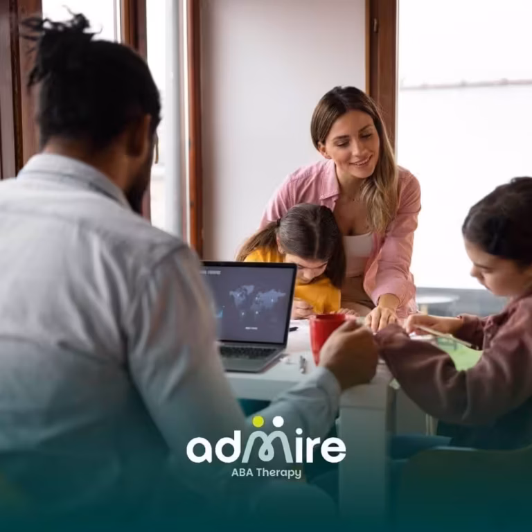 Therapist & autistic kids work together at a table with a laptop, creating art and learning together in a bright family home.