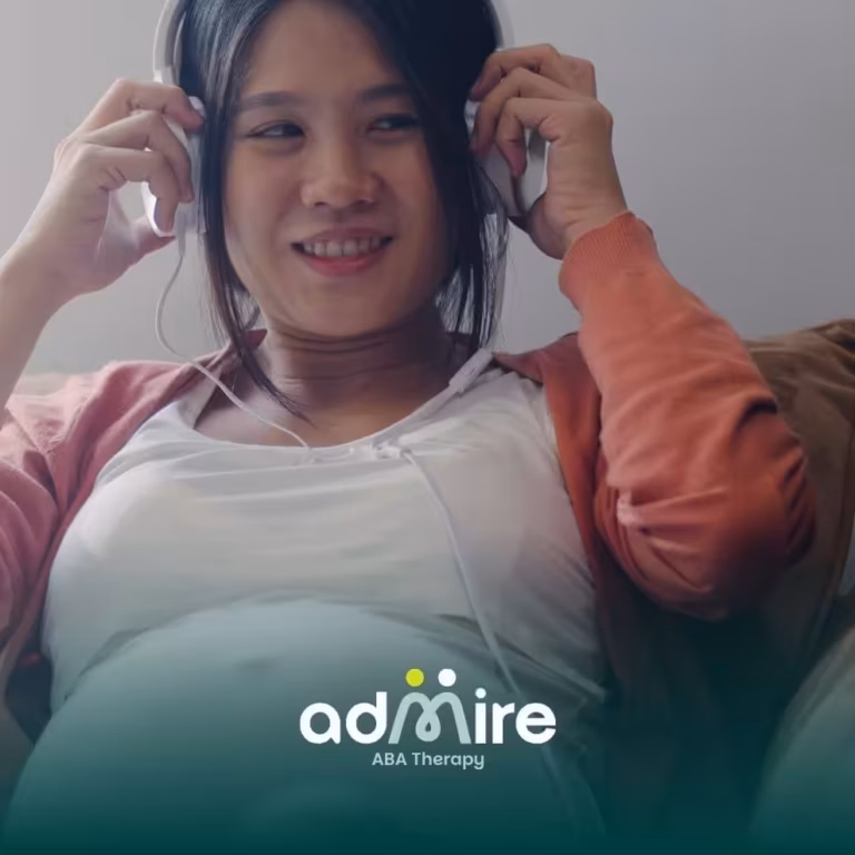 Pregnant woman sitting comfortably on a couch wearing headphones and smiling, representing relaxation.