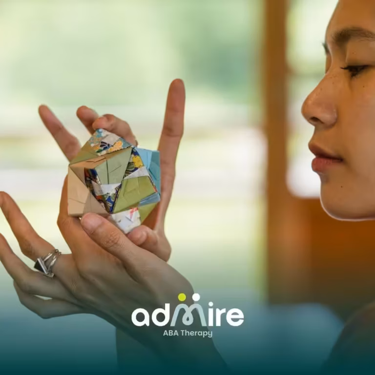 Therapist examines folded origami, modeling focus, problem-solving, and sensory engagement for learning.