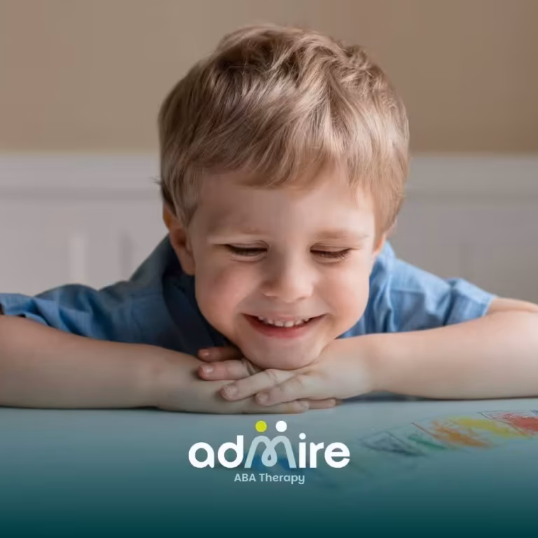 Happy autistic child smiling at their artwork on a table, reflecting confidence, creativity, and positive reinforcement.