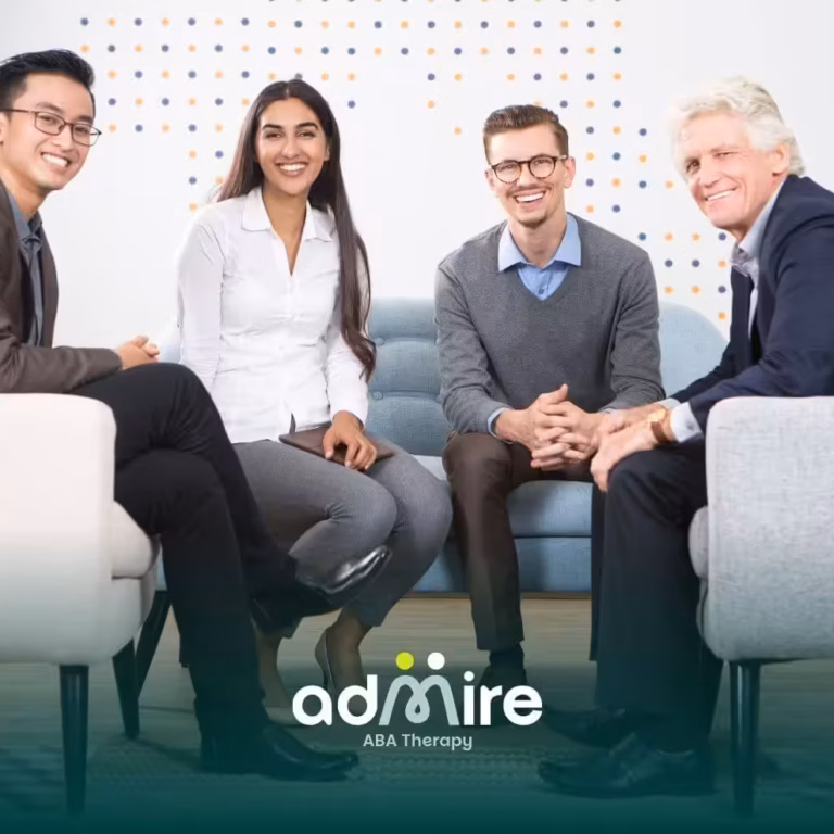 Group of therapists sitting together in a meeting, smiling & engaging in collaborative discussion in a modern office setting
