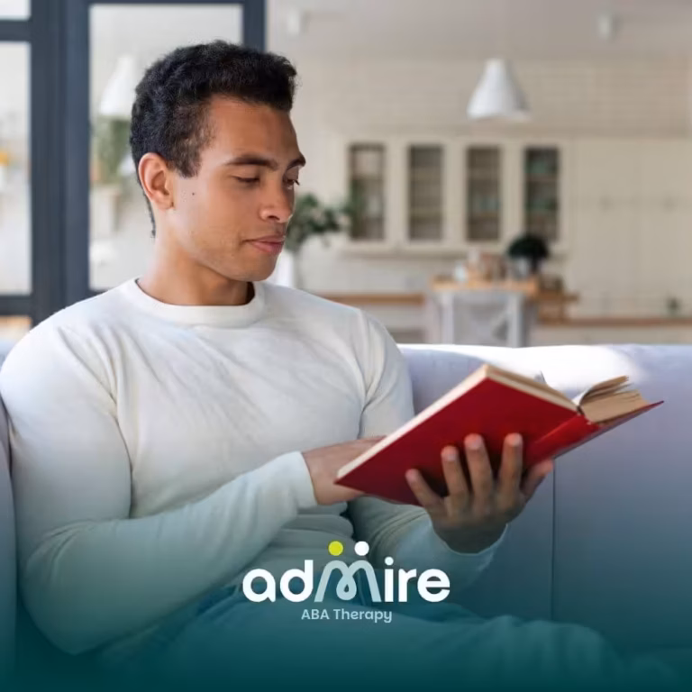 Male therapist reading a book in a calm home setting, representing learning, awareness, & understanding the history of autism